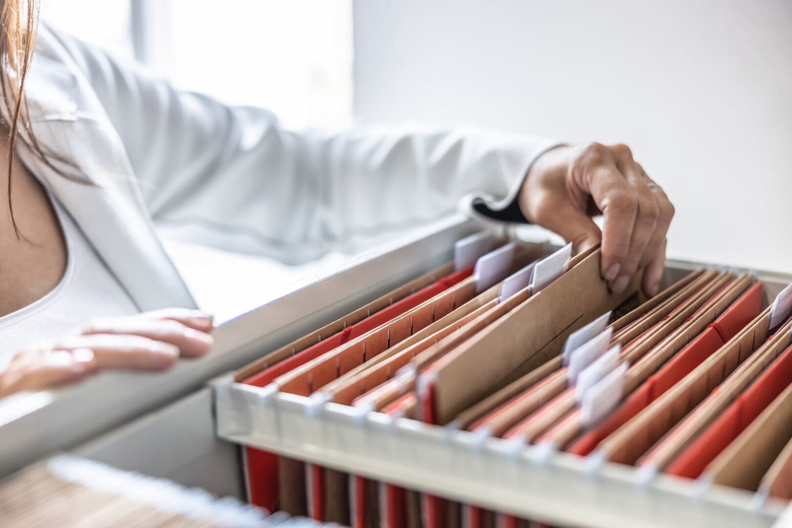 Person organizing files in a cabinet drawer.