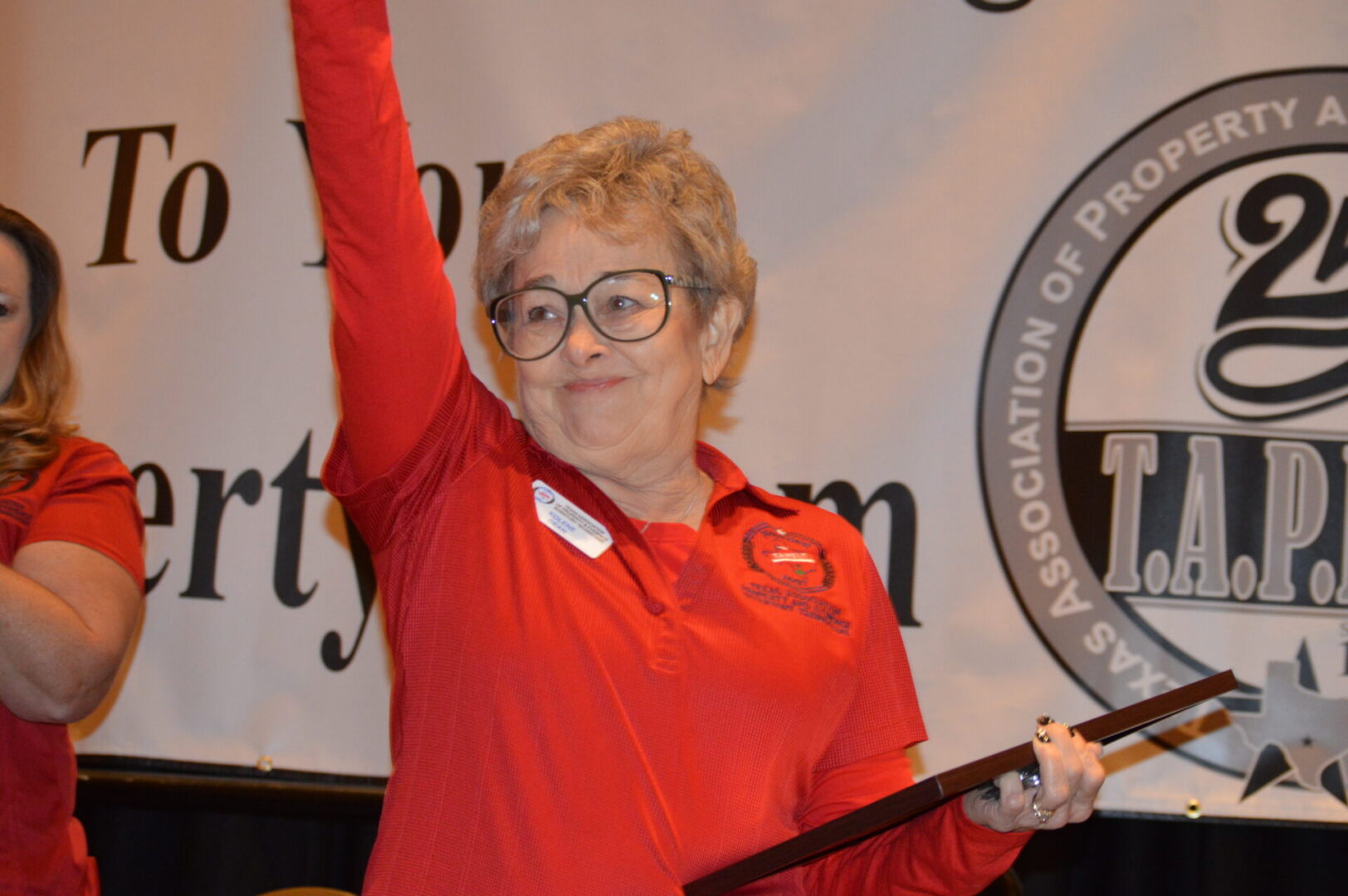Smiling woman in red shirt raising hand