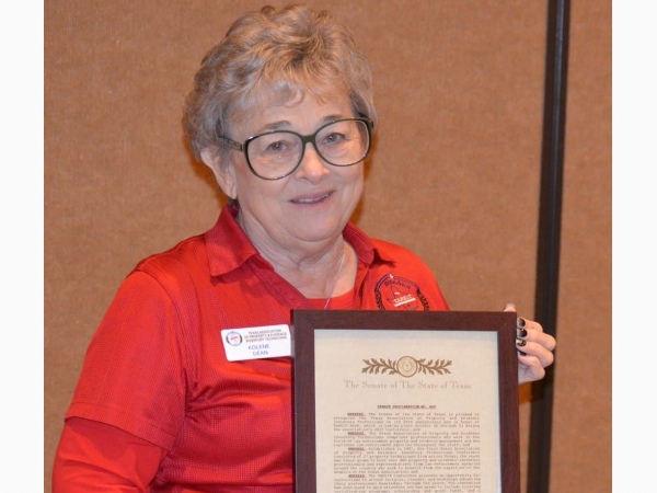 Smiling woman in red shirt holding framed certificate
