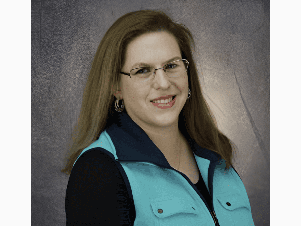 Smiling woman wearing glasses and teal vest