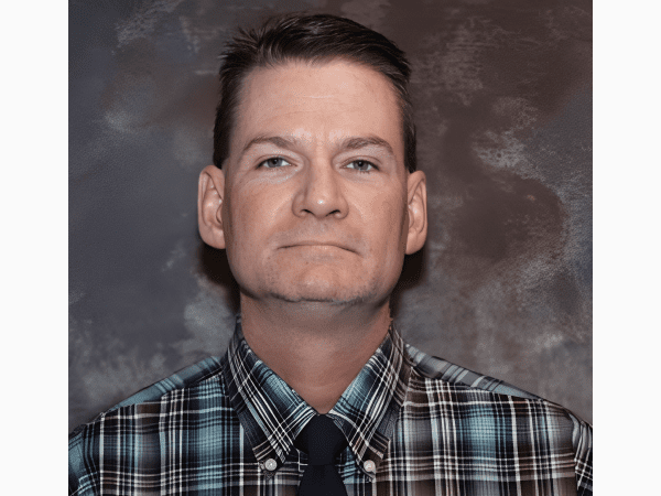 Headshot of man in plaid shirt and tie