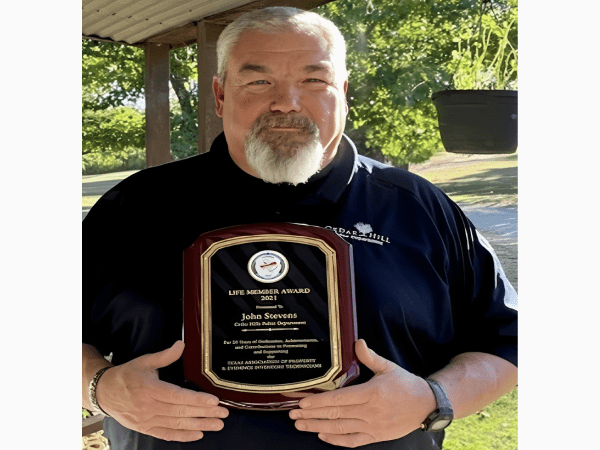 Smiling man holding award plaque outdoors